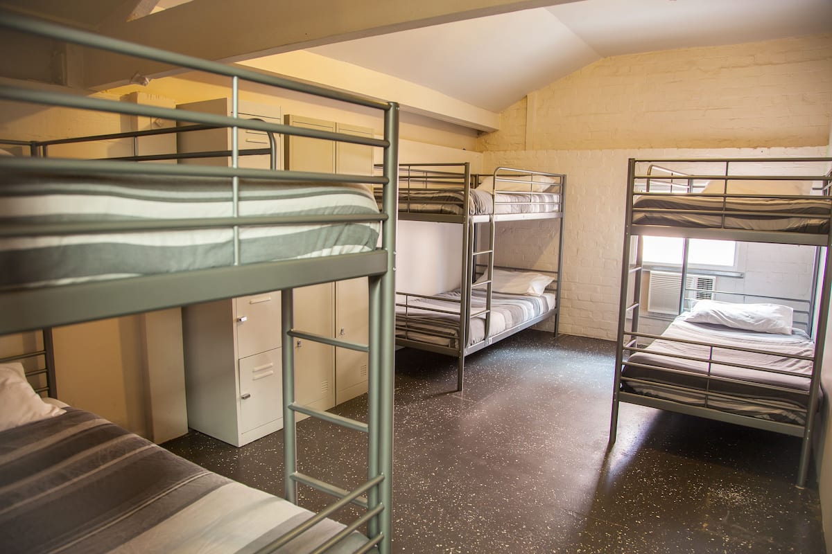 Ein Schlafsaalzimmer mit Etagenbetten, einem Schreibtisch und einem Kleiderschrank.