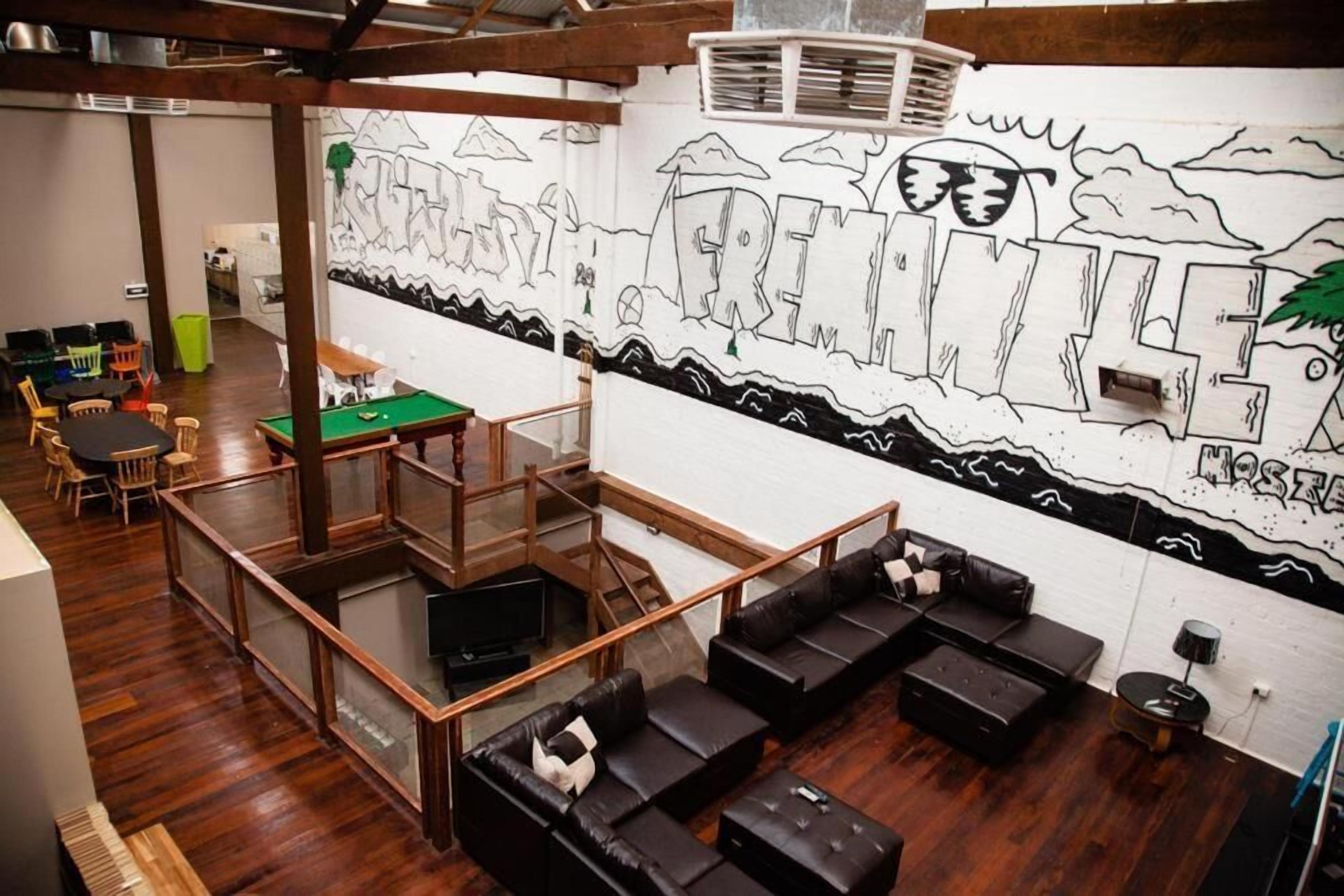 A modern lounge area with a pool table, sofas, and a mural on the wall.