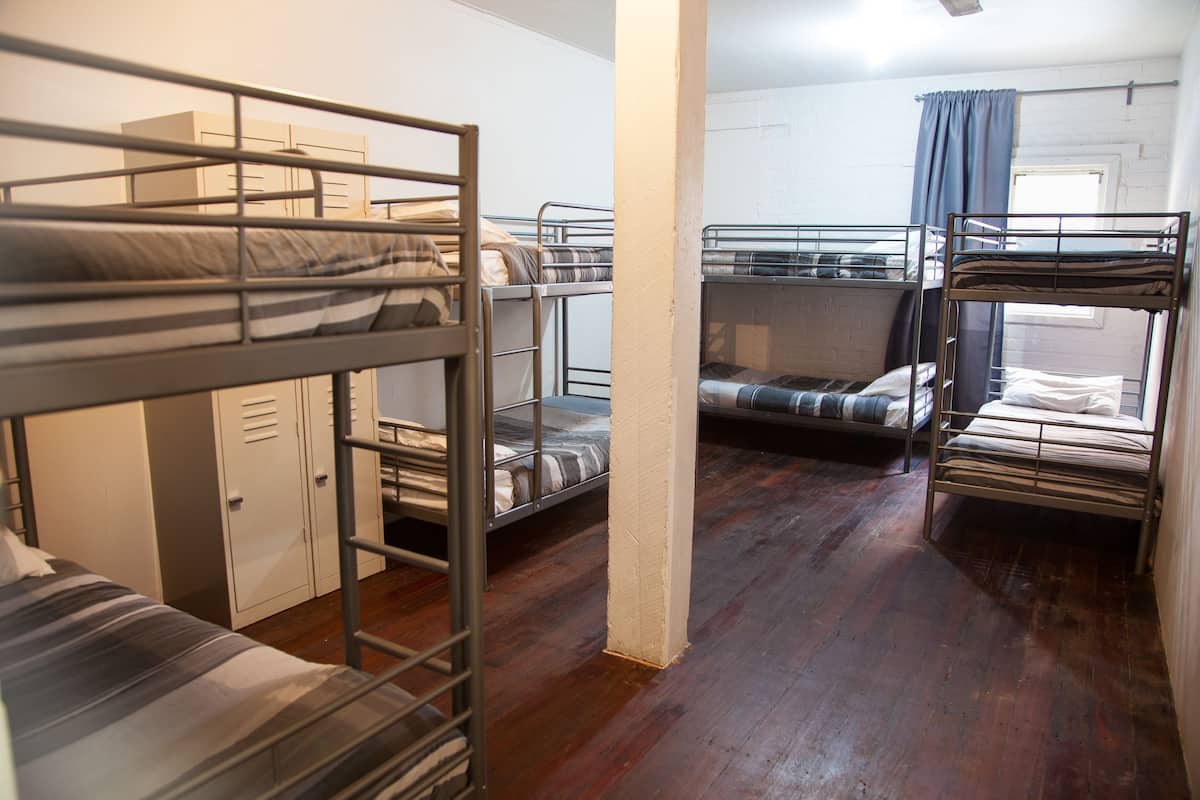 Ein Schlafsaalzimmer mit Etagenbetten, einem Kleiderschrank und einem Fenster mit Vorhängen.
