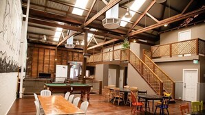 Un grand espace intérieur comprenant une table de billard, plusieurs tables à manger et un escalier.