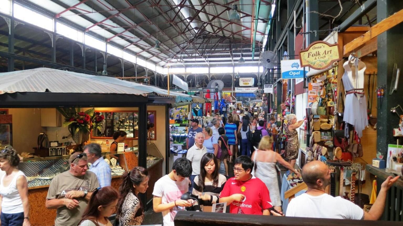 A bustling indoor market with various stalls and a high ceiling.