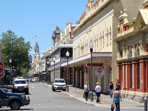 A street with historic buildings, a 'No Entry' sign, and pedestrians.
