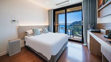 Une chambre d’hôtel moderne avec un grand lit, un bureau et une vue sur la mer.