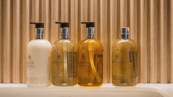 Cuatro botellas de productos para el cabello de Molton Brown London sobre un estante blanco.
