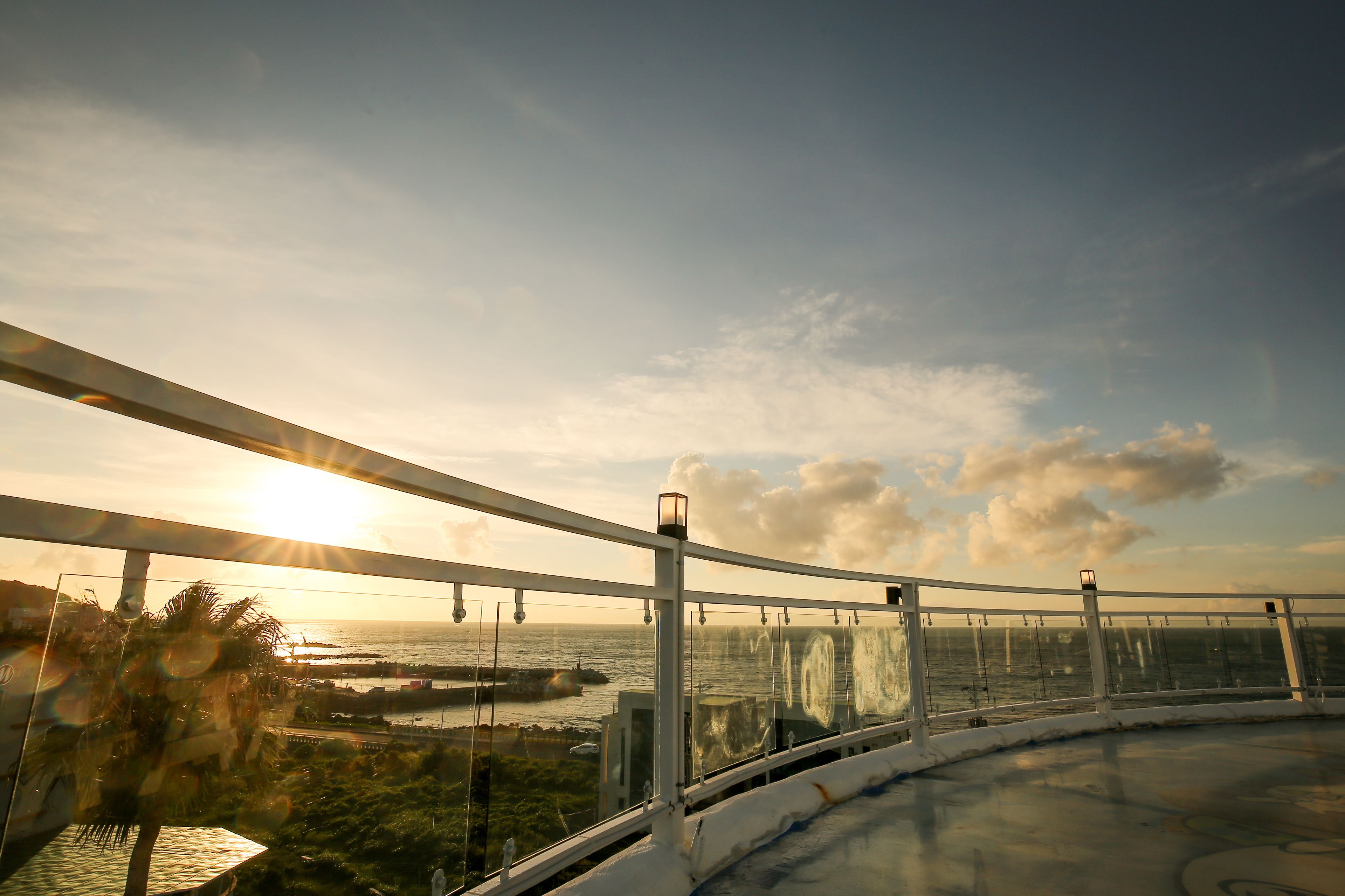 Panoramisch uitzicht vanaf een hoog punt met uitzicht op een kustgebied, heldere lucht en een ondergaande of opkomende zon.