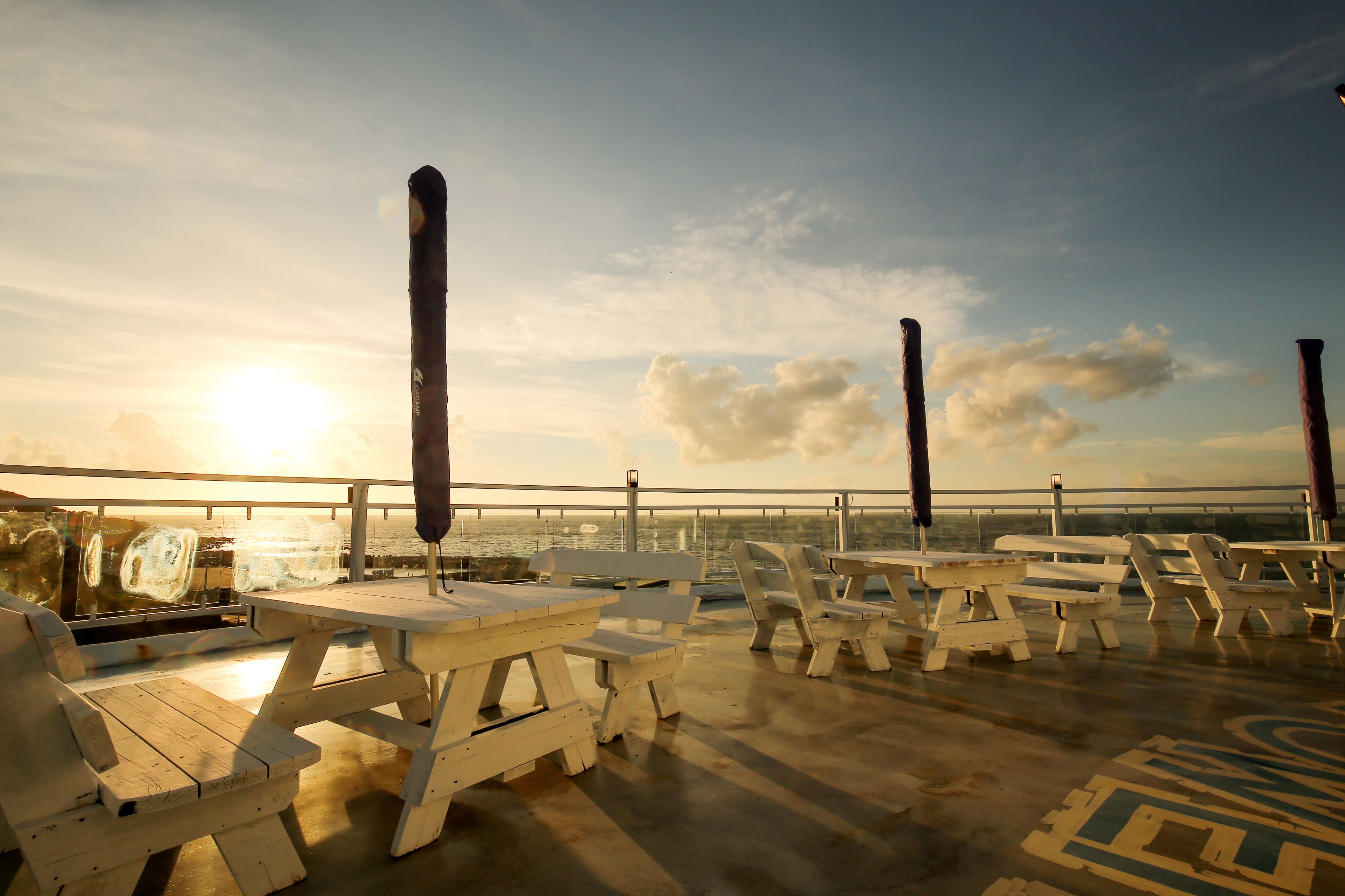 Une terrasse avec des tables et des chaises pour pique-niquer, donnant sur un plan d’eau.