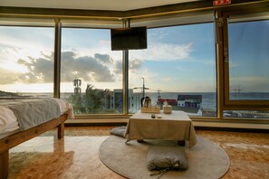 A hotel room with a bed, a round table with a tablecloth, and a TV on the wall. - Pure Stay Ocean (Jeju City)