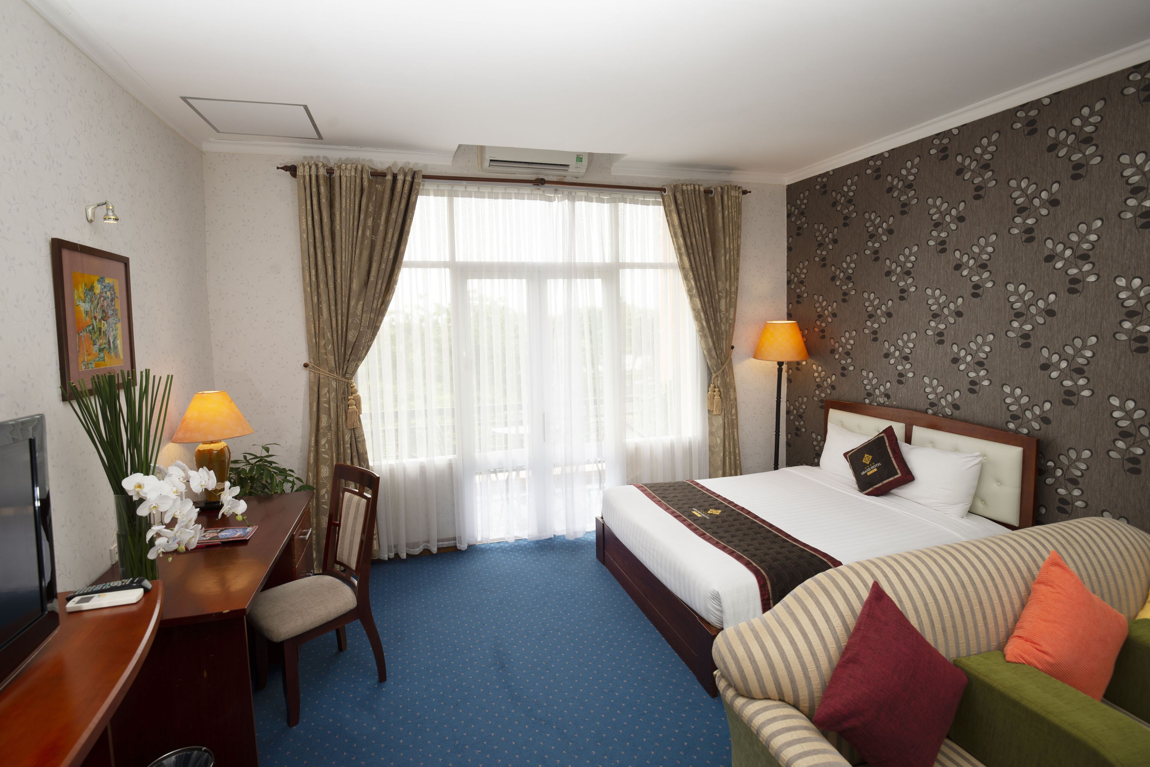 Een hotelkamer met een bed, een bureau, een stoel, een televisie en een raam met gordijnen.