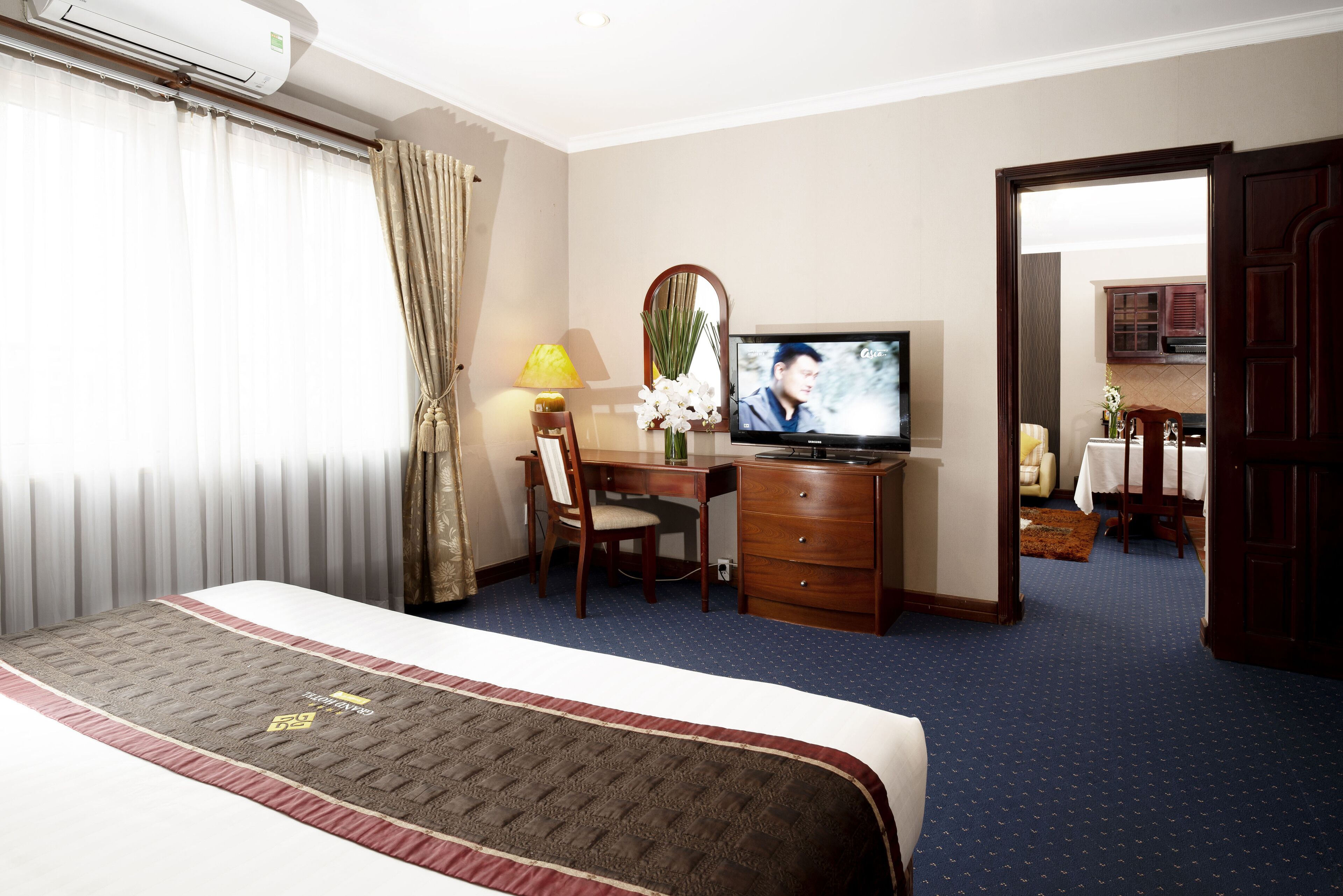 A hotel room with a bed, a desk, a television, and a mirror.
