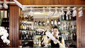 Un bar con estantes llenos de botellas de licor y copas de vino colgando.