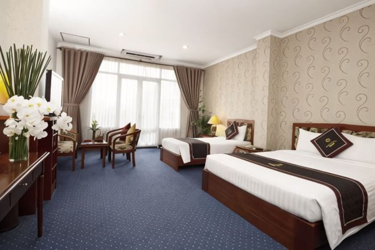 A hotel room with two beds, a desk, a chair, and a window with curtains.