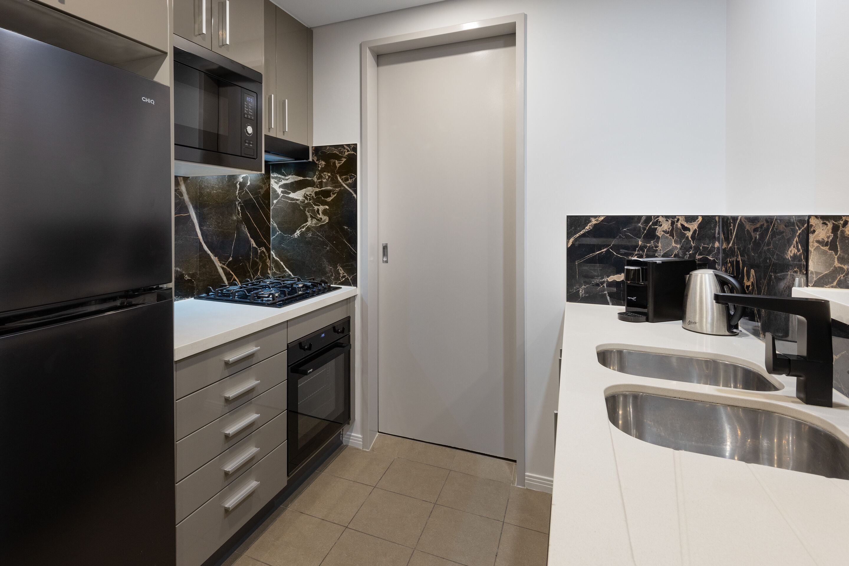 Une cuisine moderne équipée d’un four encastré, d’un four à micro-ondes et d’une cuisinière à gaz.