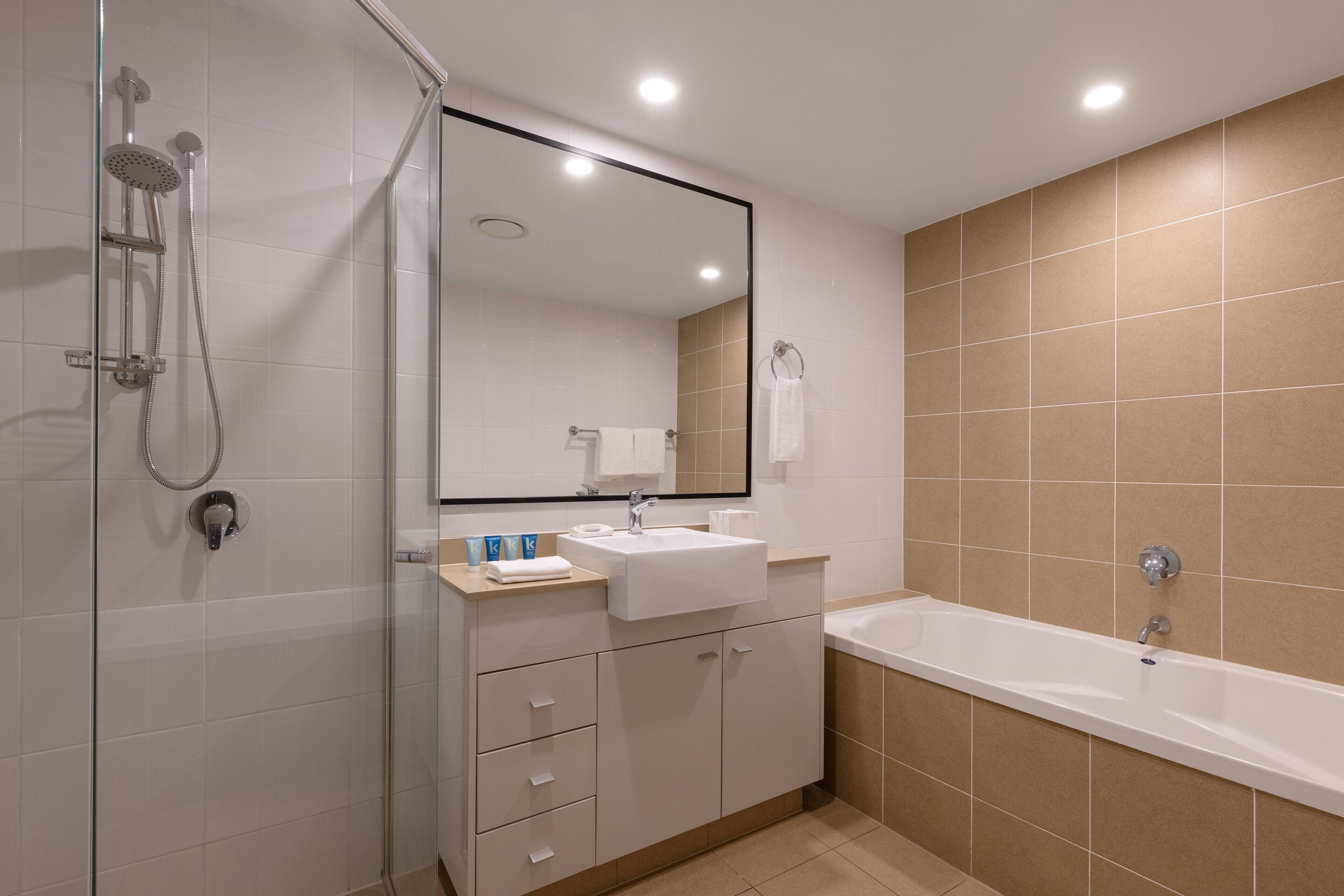 A modern bathroom with a glass-enclosed shower, a white sink, and a bathtub.
