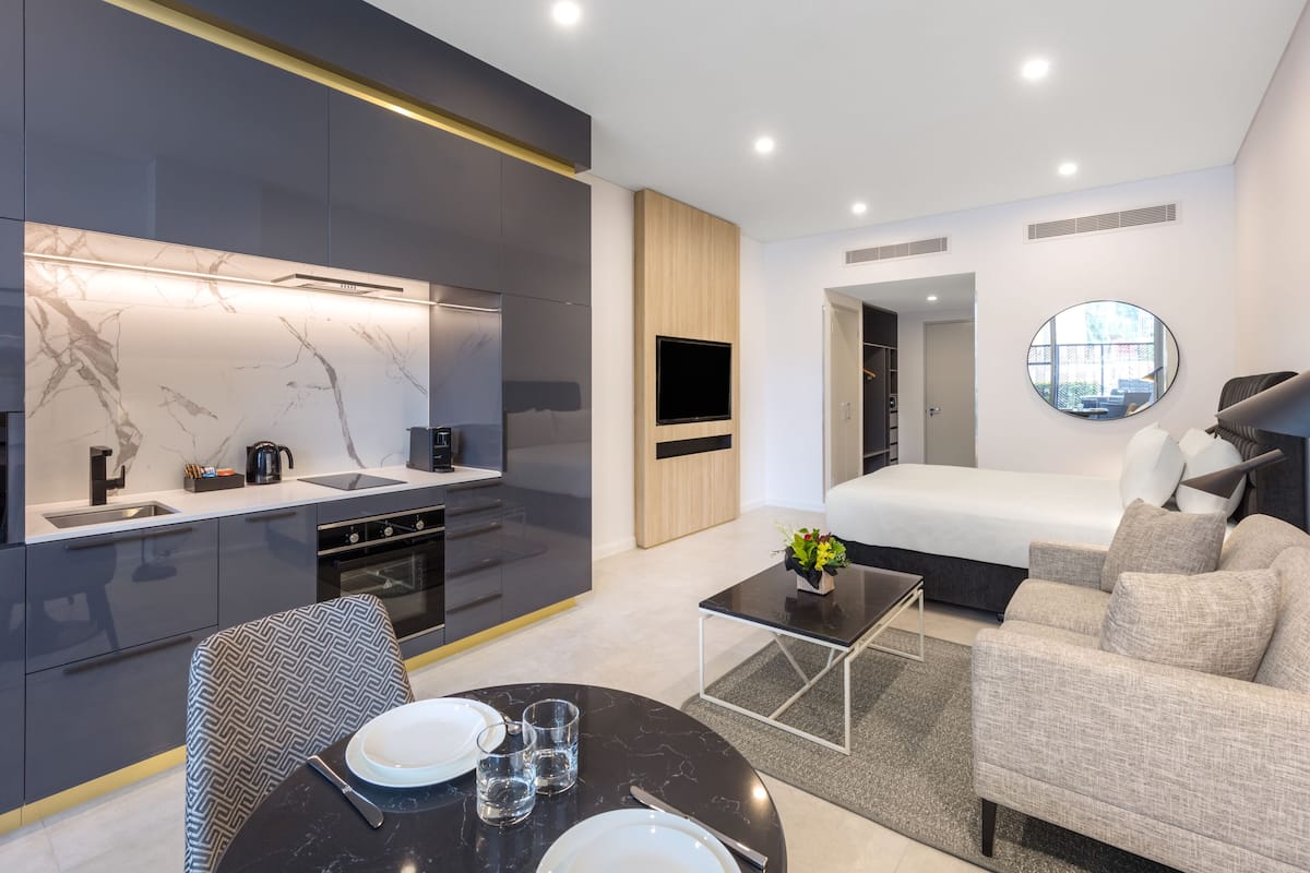 A modern, compact living space with a kitchen, dining area, and a bedroom.