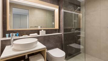 A modern bathroom with a large mirror, a sink, a toilet, and a glass-enclosed shower area.
