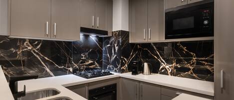 A modern kitchen with a gas stove, built-in oven, stainless steel sink, and a microwave.