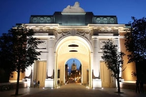 An illuminated archway leading to a historic building with a clock tower.