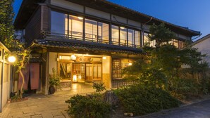 Une maison traditionnelle japonaise, avec une façade en bois, de grandes fenêtres et une entrée bien éclairée.