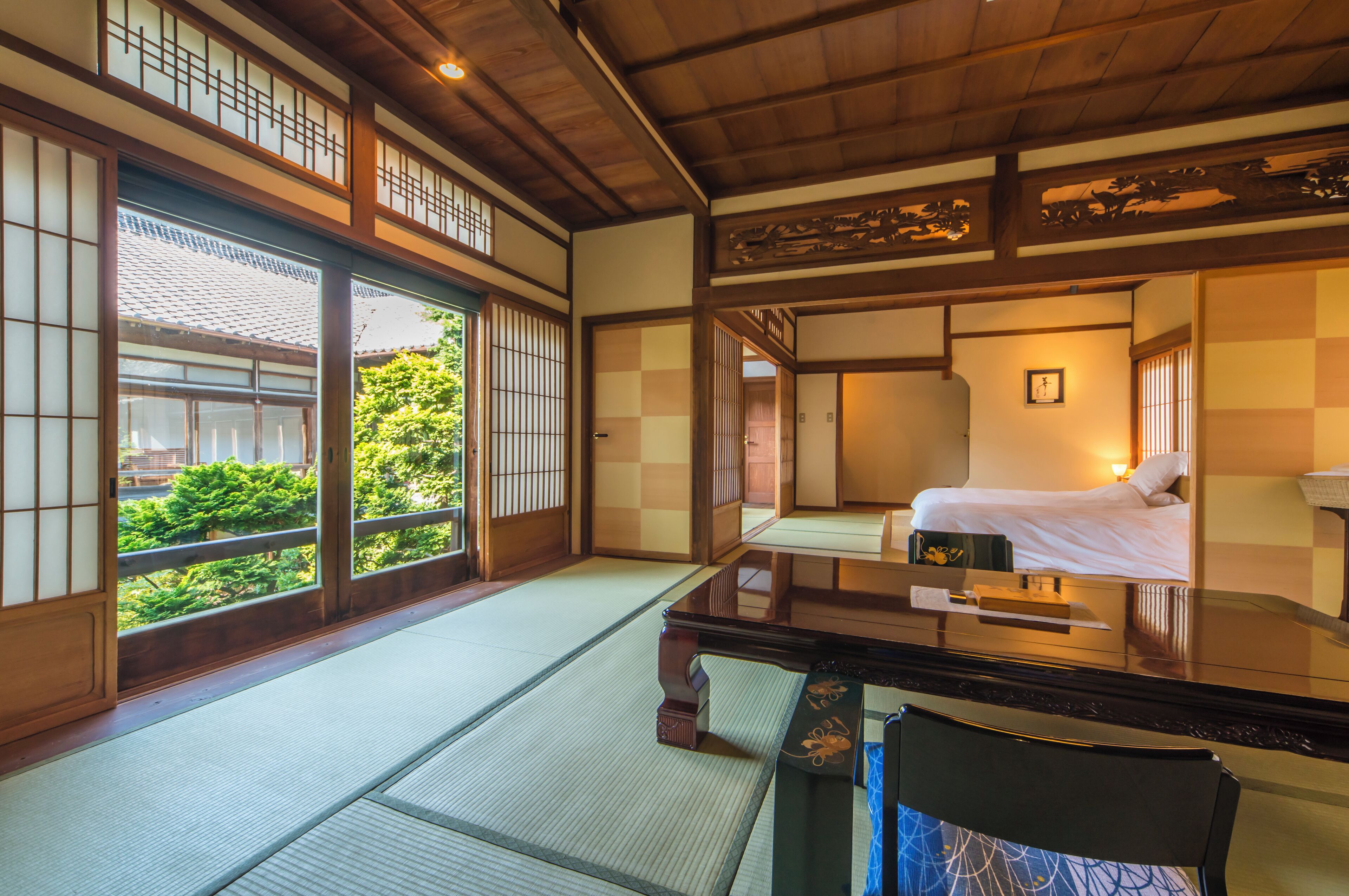 A traditional Japanese room with tatami flooring, a low table, and a bed.
