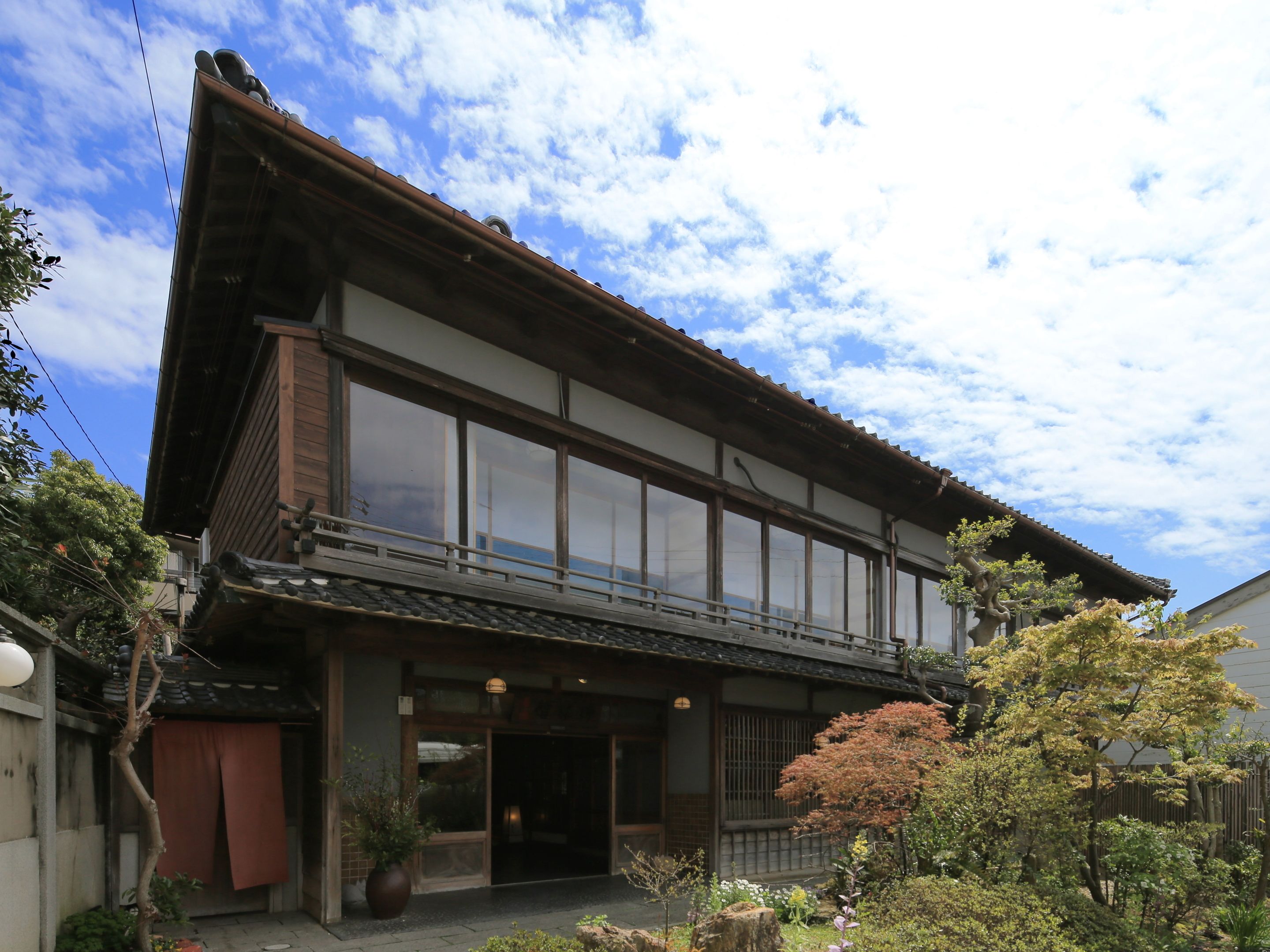 Il s’agit d’un bâtiment traditionnel japonais, avec une façade en bois, de grandes portes coulissantes et un petit balcon.