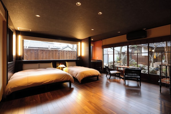 A hotel room with two beds, a desk, and a large window with a view of a garden. - Nagomi no Yado Kakujoro (Tahara)