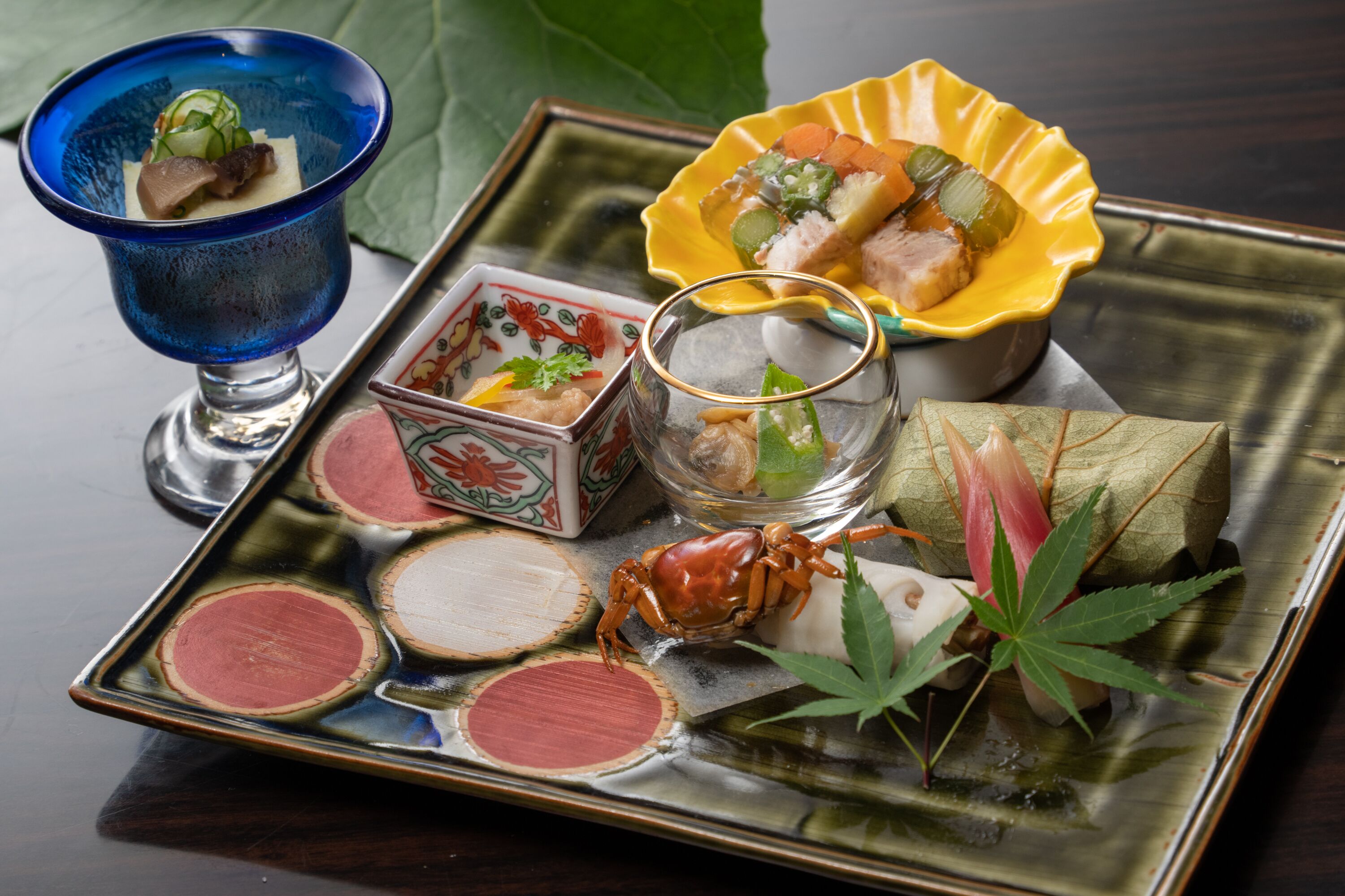 Un plateau contenant divers plats japonais, notamment des sushis, des sashimis et du crabe.