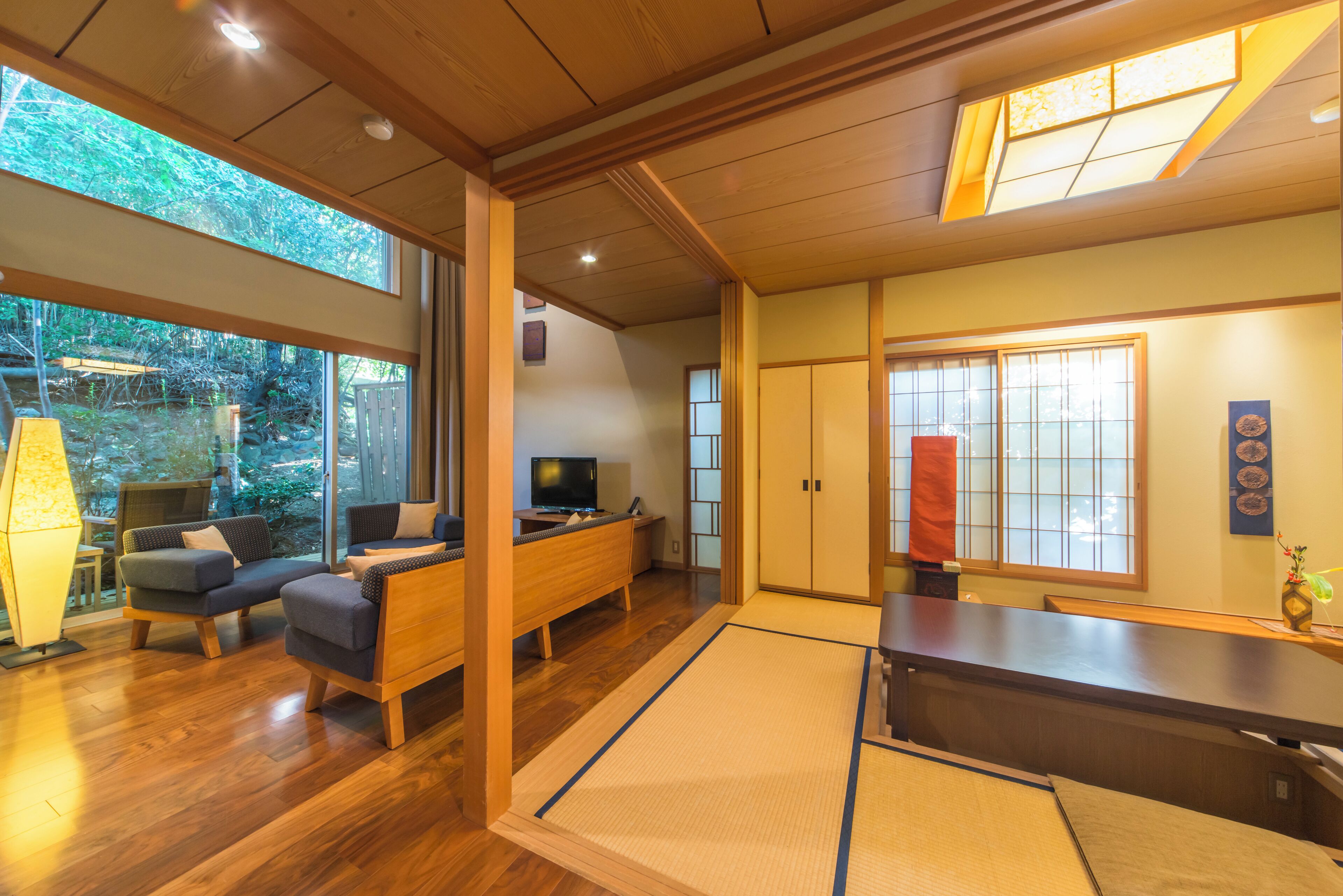 Una habitación de estilo japonés tradicional, con suelo de tatami, una mesa de madera baja y un televisor sobre un soporte de madera.