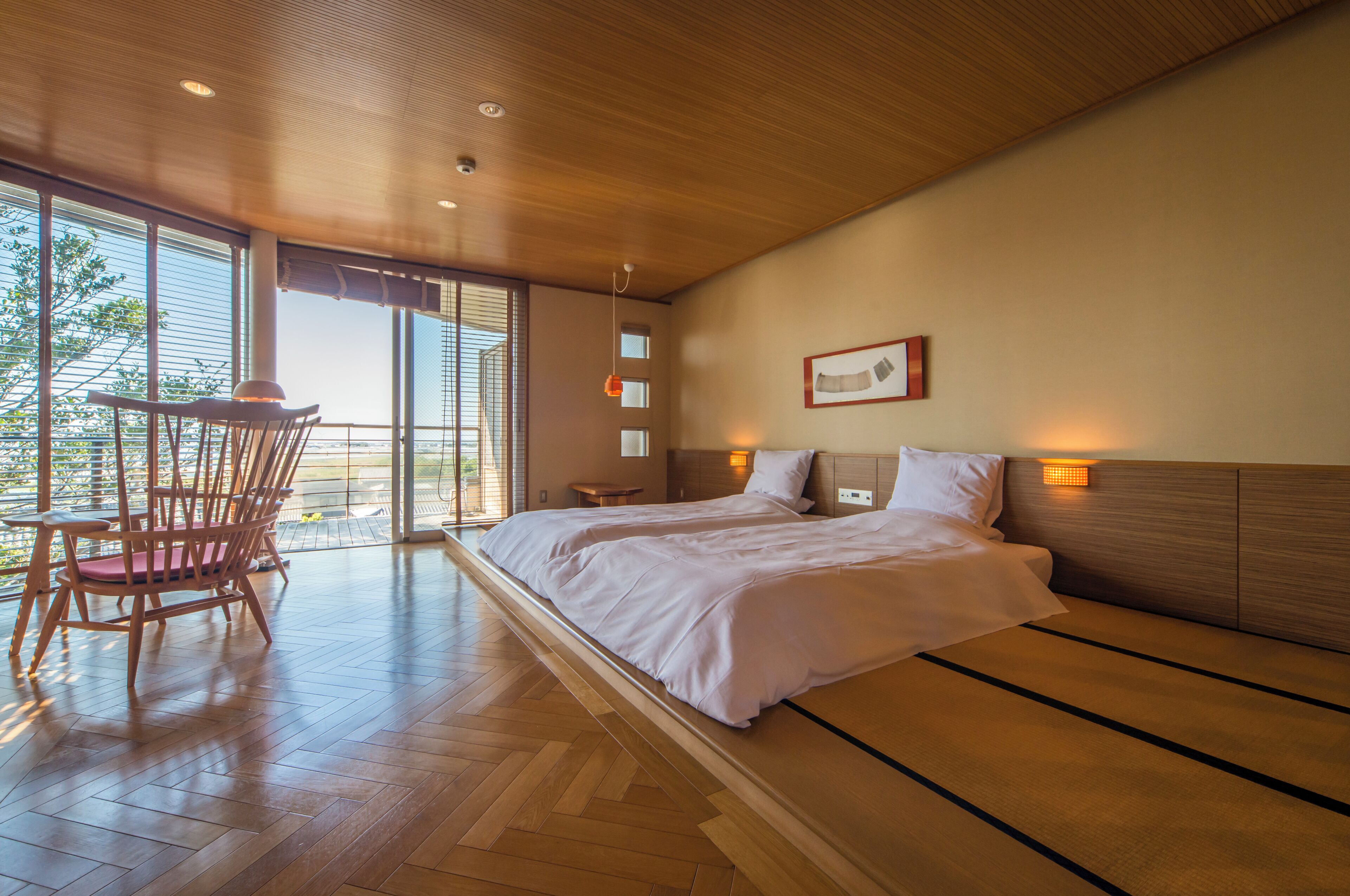 Un dormitorio moderno con una cama grande, suelo de madera y vistas a través de la ventana.