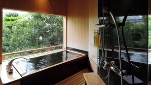 Un intérieur en bois avec un bain à remous, un petit tabouret en bois et un espace douche.