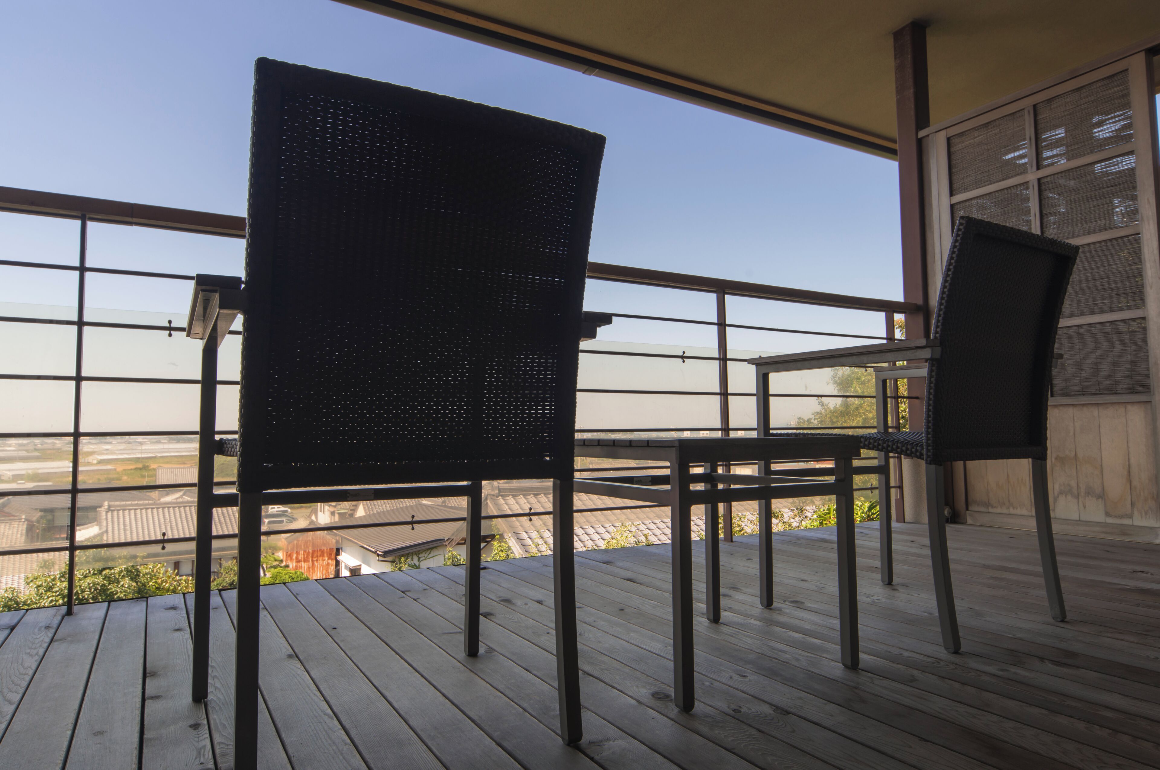 Un balcon avec deux chaises et une table, donnant sur un paysage urbain.