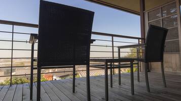 Un balcon avec deux chaises et une table, donnant sur un paysage urbain.