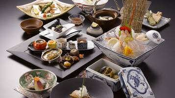 Une variété de plats japonais présentés sur une table, notamment des sushis, des sashimis et d’autres spécialités à base de fruits de mer.