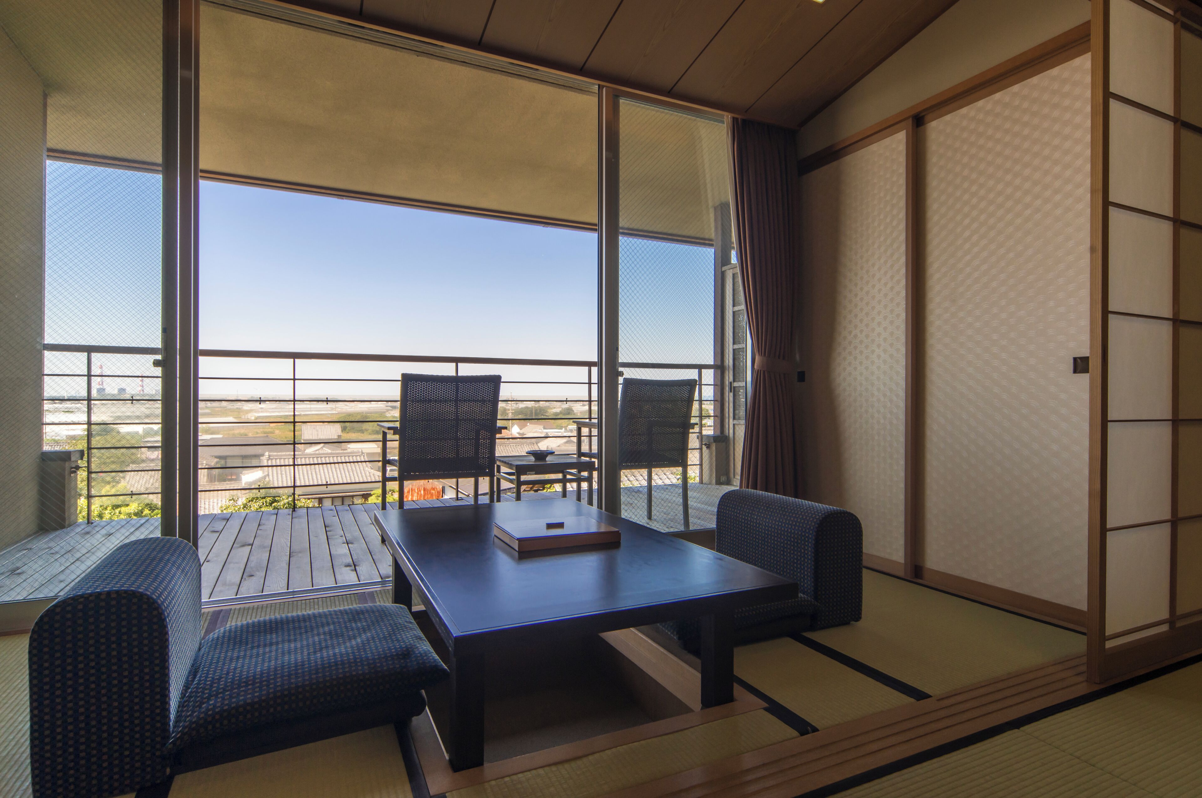 A traditional Japanese room with tatami flooring, a low table with cushions, and sliding doors.