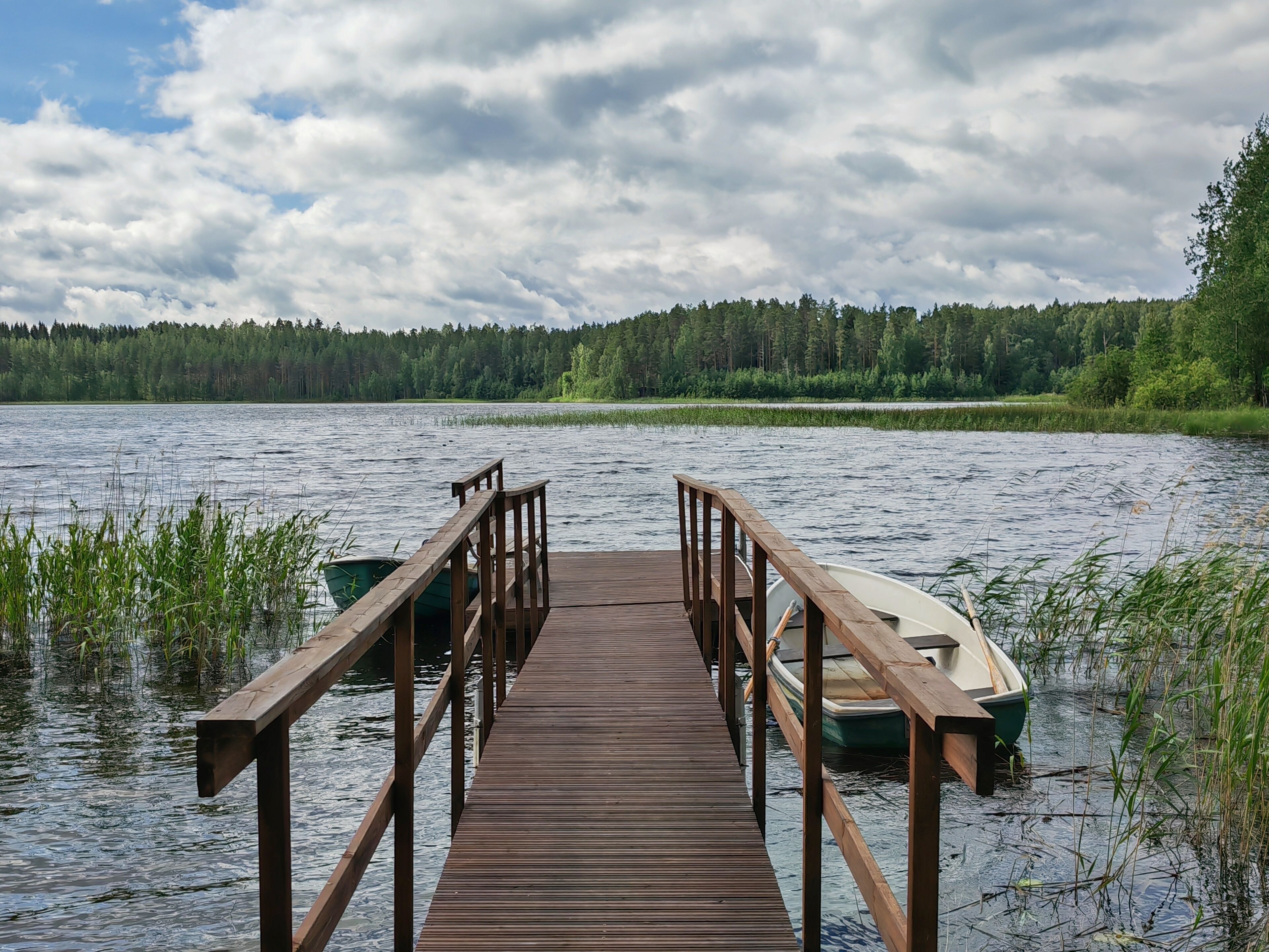 A wooden pier extending into a lake with boats docked at the end.