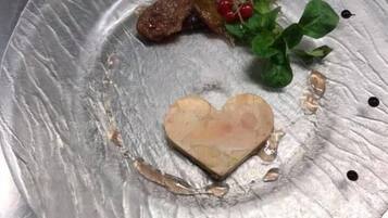 A heart-shaped food item on a metallic plate with some greens and berries.