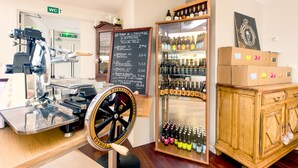 A coffee shop interior with a coffee machine, a menu board, a wine cooler, and wooden cabinets. - Notre Dame (Haguenau)