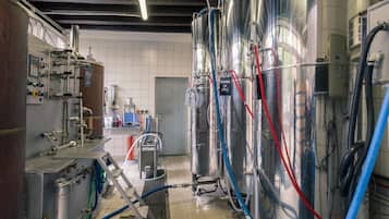 A brewery with stainless steel tanks, control panels, and hoses.