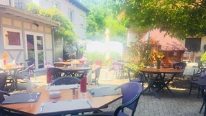 An outdoor dining area with brick flooring, tables, and chairs. - Notre Dame (Haguenau)