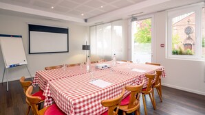 A conference room with a whiteboard, a projector screen, and a table set for a meeting. - Notre Dame (Haguenau)