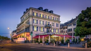 Un hôtel à plusieurs étages, doté d’une entrée imposante, d’espaces extérieurs aménagés et d’un restaurant bien visible appelé « La Brasserie du Rivere ».