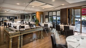 Un restaurant doté de nombreuses tables, d’un bar central et offrant une vue sur l’espace extérieur aménagé pour les clients.