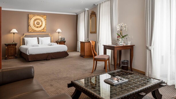 Une chambre d’hôtel comprenant un lit, un bureau, une chaise, une table basse et un grand miroir.
