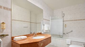 A bathroom with a marble sink, a glass shower enclosure, and a white toilet.