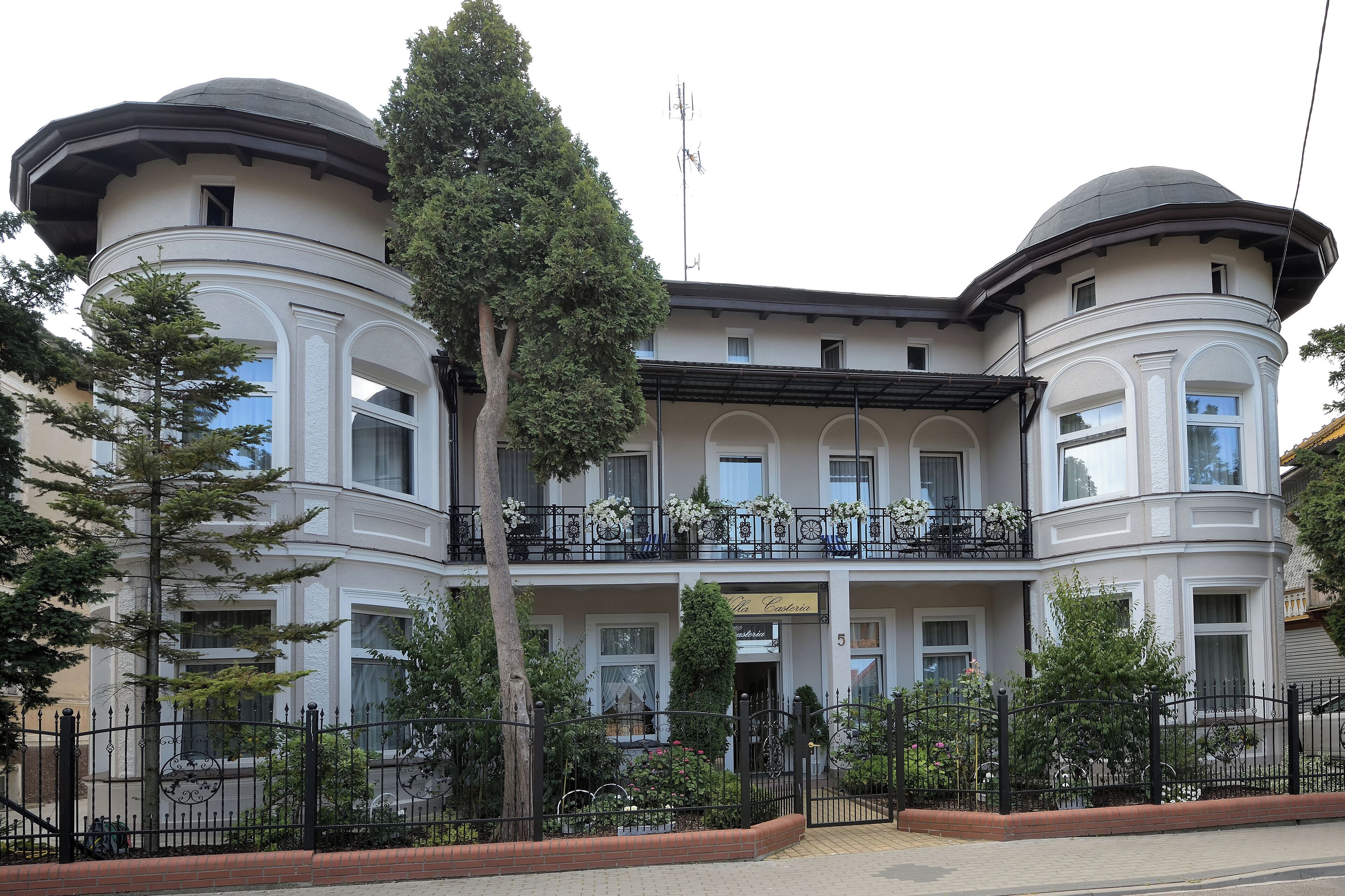 A large, historic building with a central balcony and two round towers.
