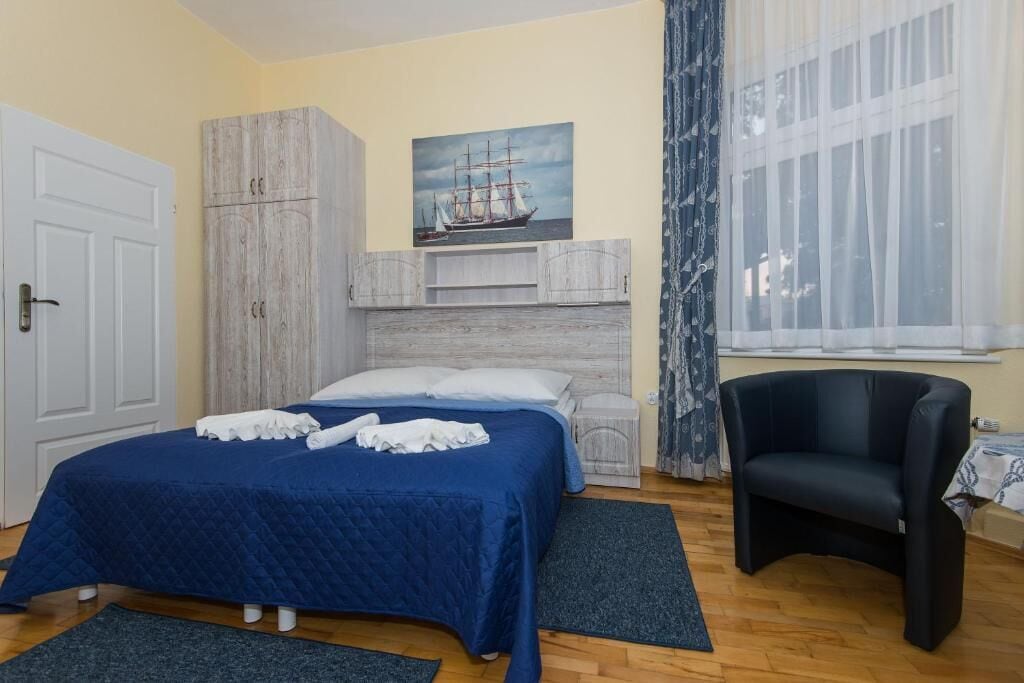 Une chambre à coucher avec un lit, une armoire, une chaise et un tableau au mur.