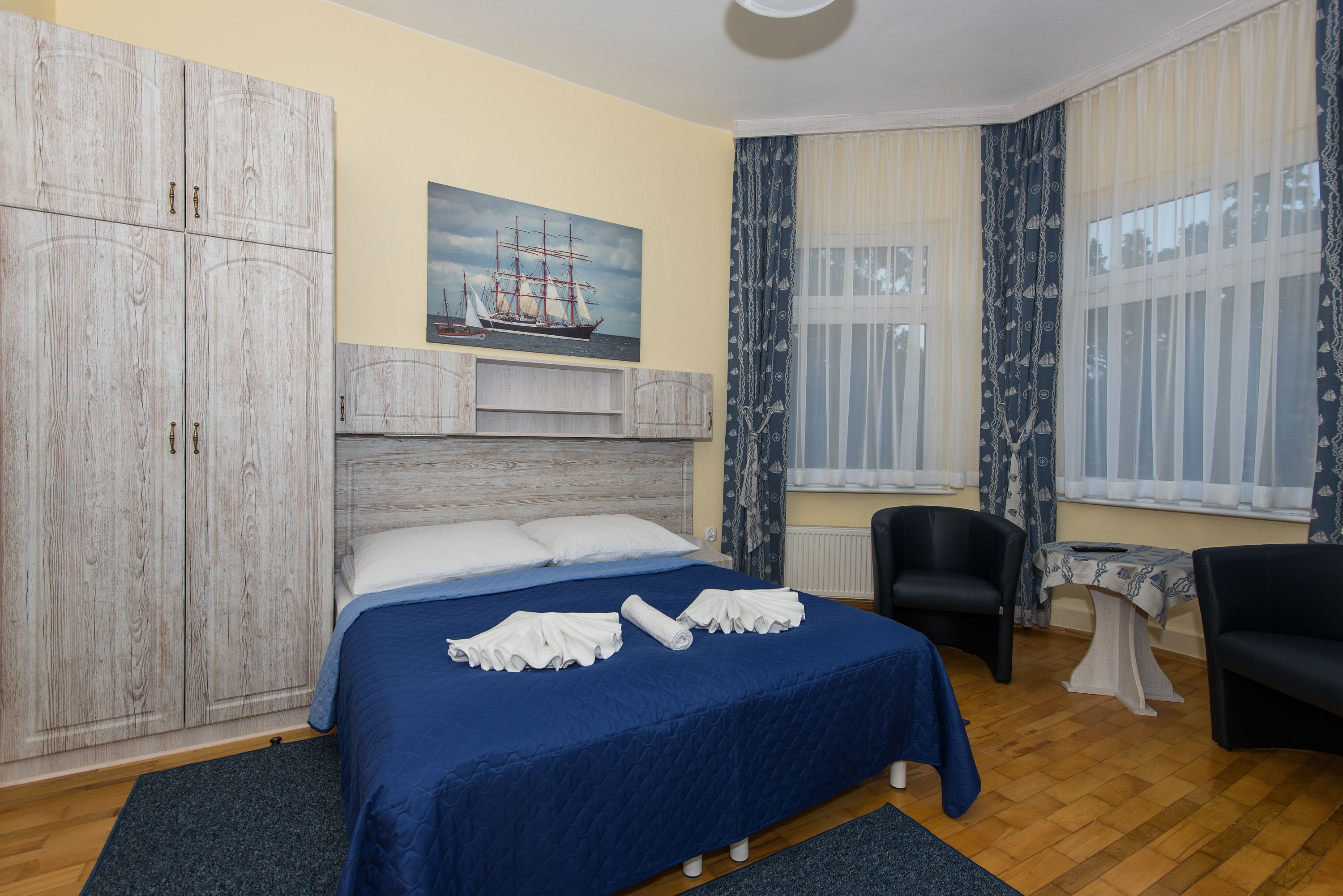 A bedroom with a large bed, a wardrobe, a desk, and a chair.