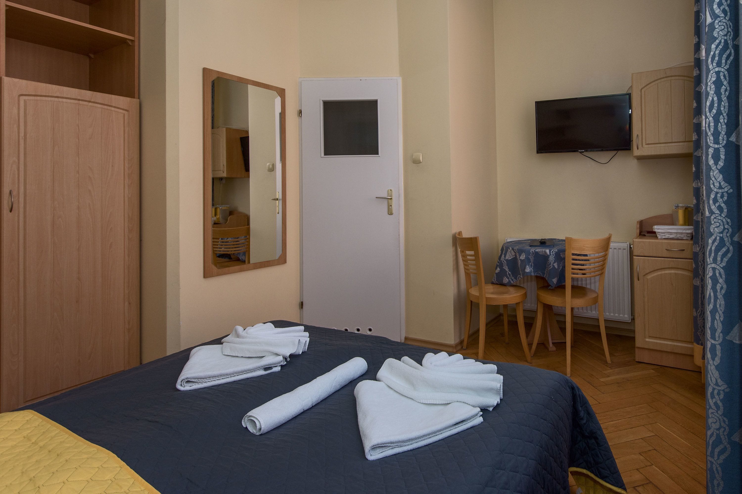 Et hotelværelse med seng, skrivebord, stol, fjernsyn og garderobeskab.