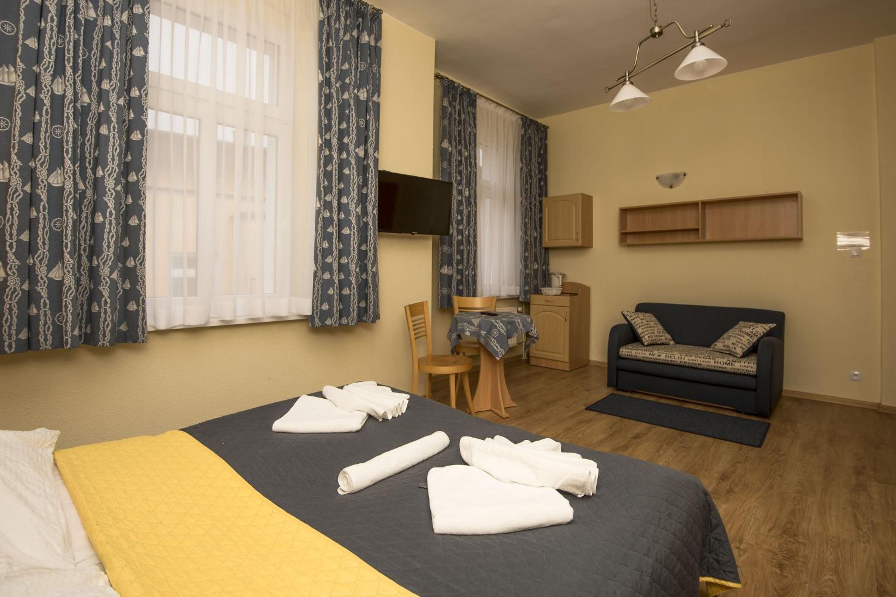 Ein Hotelzimmer mit einem Bett, einem Schreibtisch, einem Sessel, einer Couch und einem Fernseher.