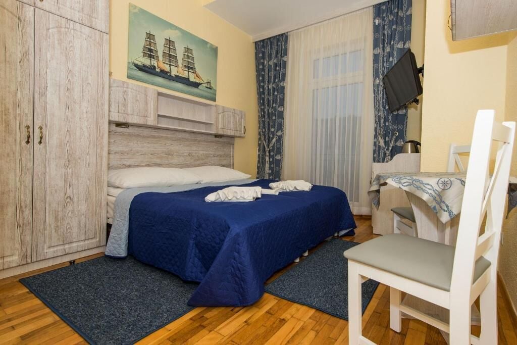 Een hotelkamer met een bed, een bureau, een stoel, een televisie en een schilderij aan de muur.