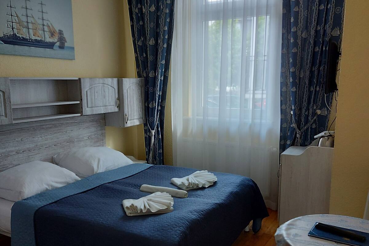 A hotel room with a bed, a desk, a chair, and a window with curtains.